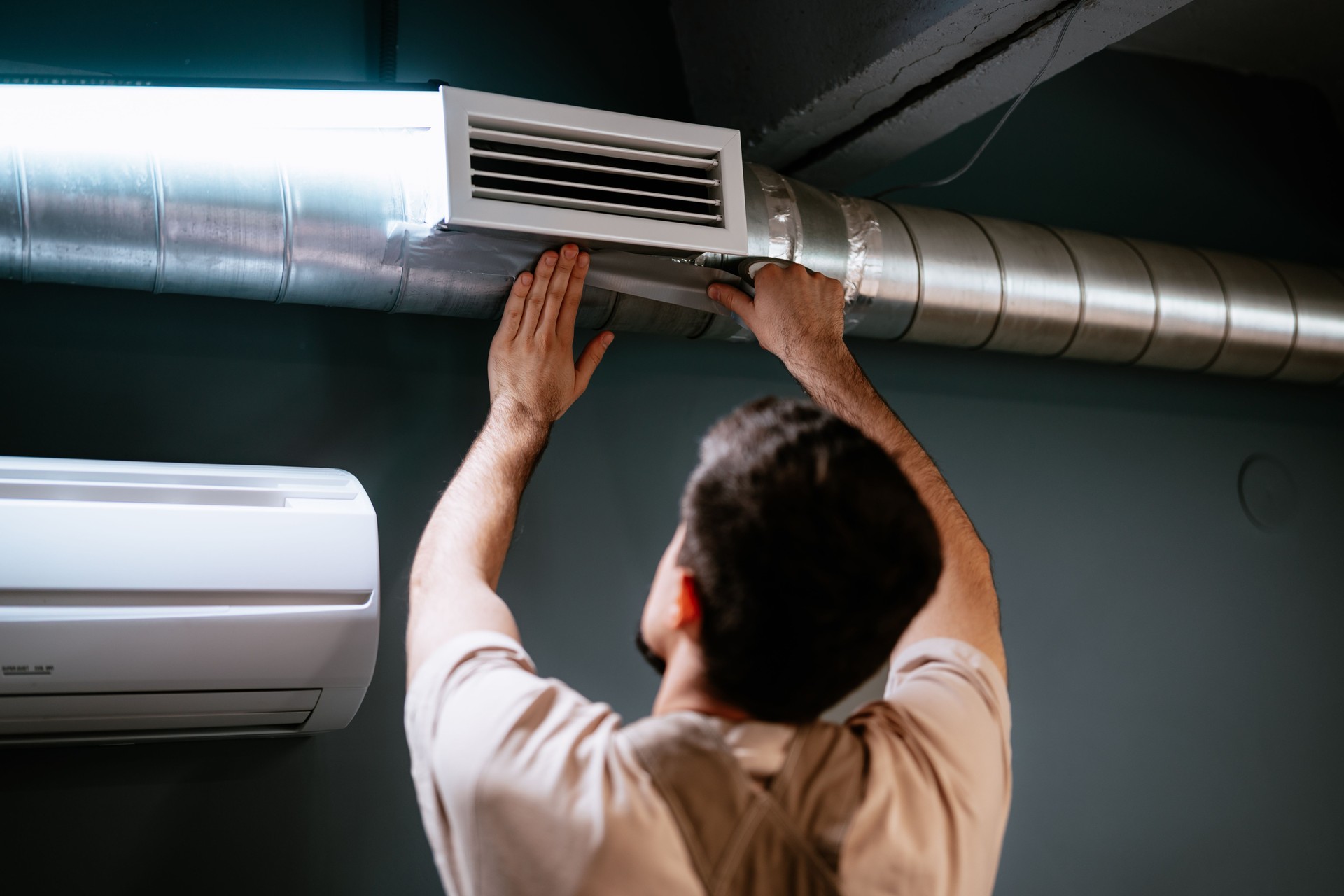 Man servicing air duct in modern interior during home improvement project in the evening