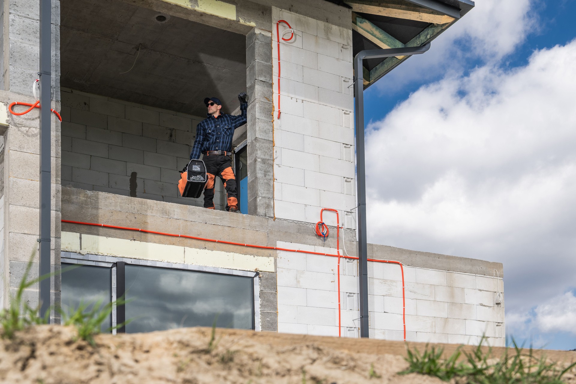 Construction Worker on Unfinished Building With Tool in Hand